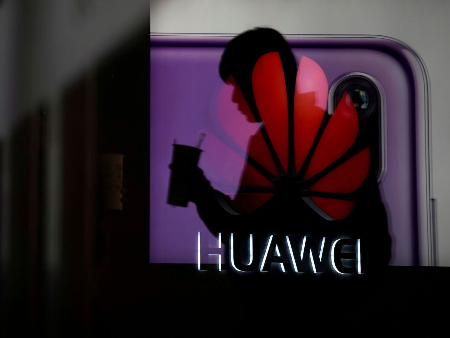 Un hombre pasa por detrás de un escaparate con un anuncio de Huawei en Shanghai, en diciembre de 2018. (Reuters)