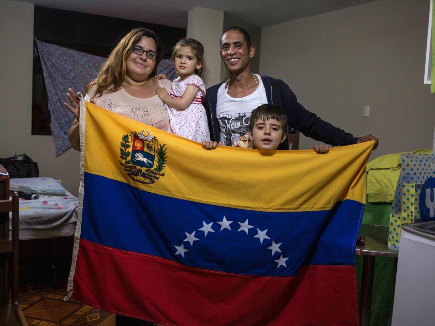 La familia posa con una bandera venezolana en su apartamento. (L. Arango)