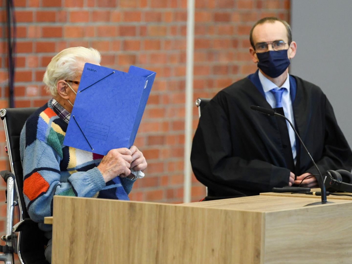 Schütz, con una carpeta cubriéndose el rostro, durante la primera vista de su juicio. (Reuters)
