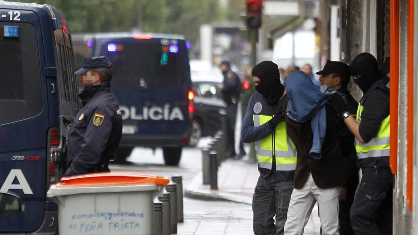 Foto: Dos efectivos de la Policía acompañan a la persona detenida este martes en el madrileño barrio de Vallecas. (EFE) 
