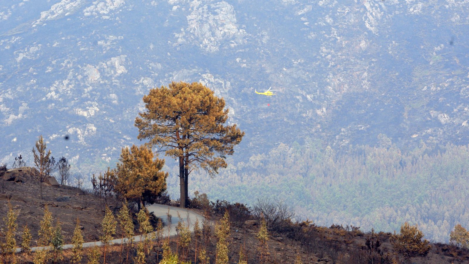 Foto: Un helicóptero en las labores de extinción del incendio en el municipio coruñés de Porto Do San. (EFE)