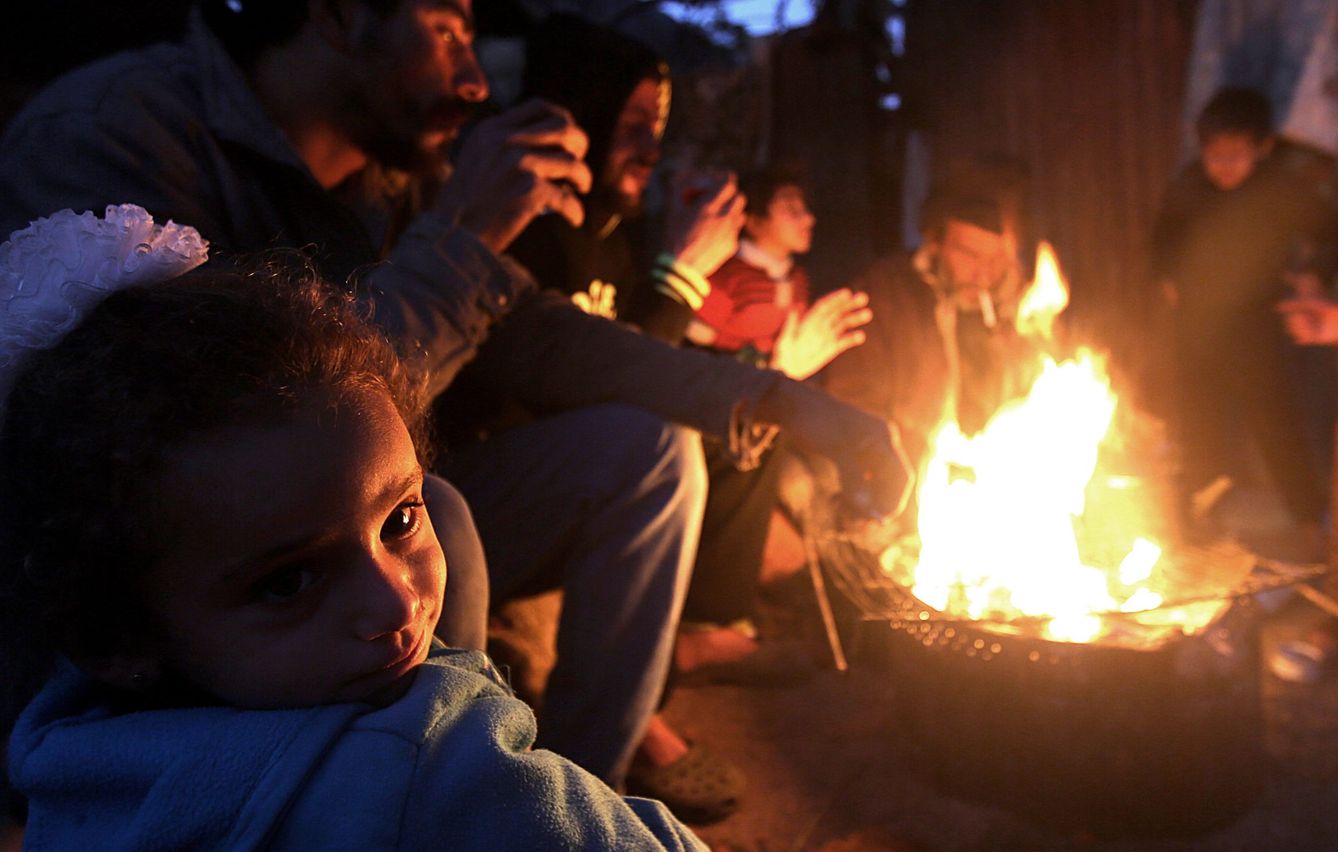Refugiados palestinos se calientan en una hoguera en el campo de Khan Younis, Gaza, el 31 de diciembre de 2016 (Reuters)