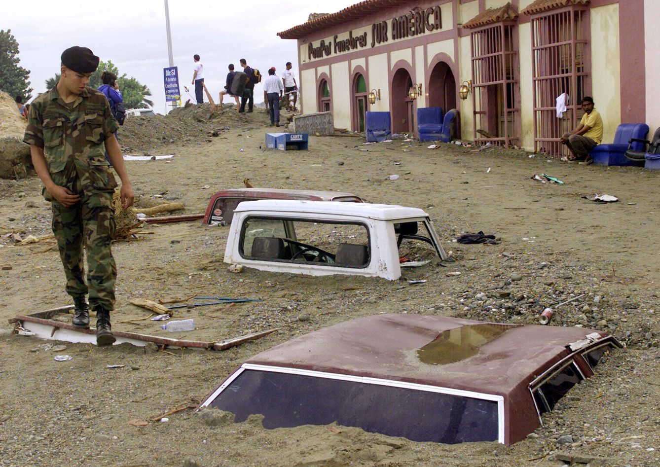 Un soldado pasa junto a coches enterrados por el barro en La Guaira tras la llamada 'tragedia de Vargas', en diciembre de 1999. (Reuters)