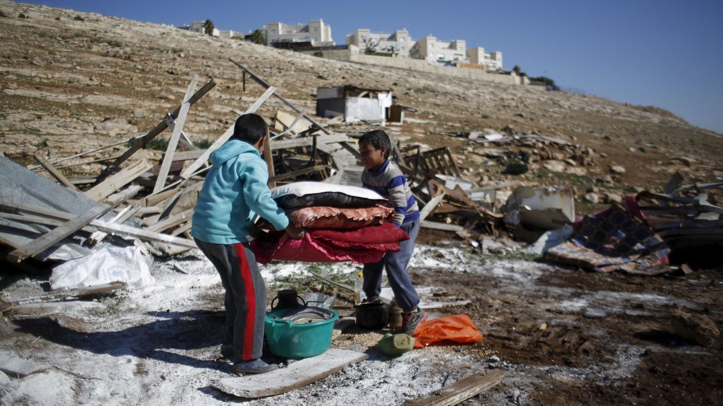 Niños palestinos cargan con sus pertenencias tras la demolición de su vivienda ante el asentamiento de Maale Adumim, cerca de Jerusalén. (Reuters)
