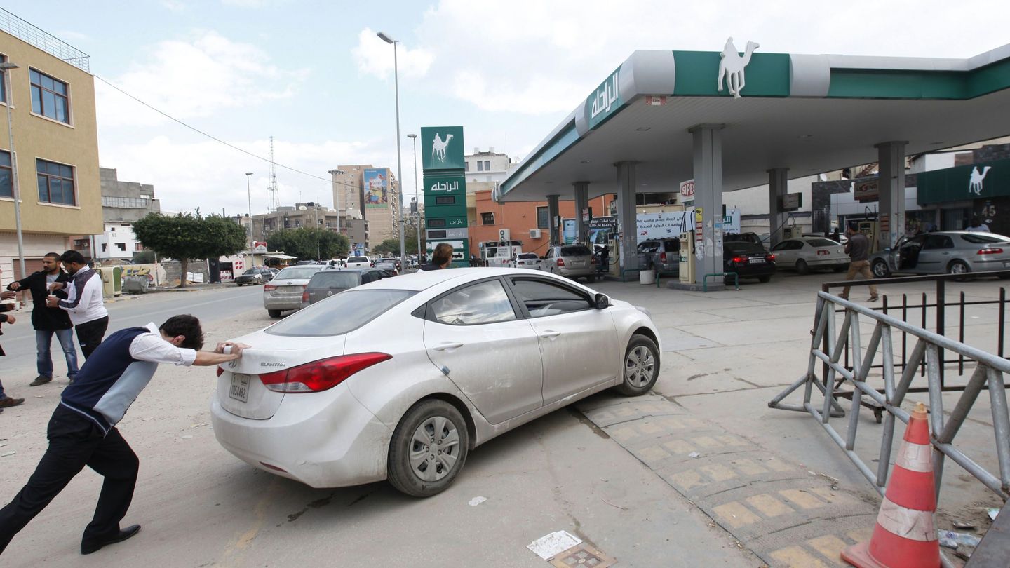 Un hombre empuja su coche hasta una estación de servicio tras quedarse sin gasolina en Trípoli (Reuters).