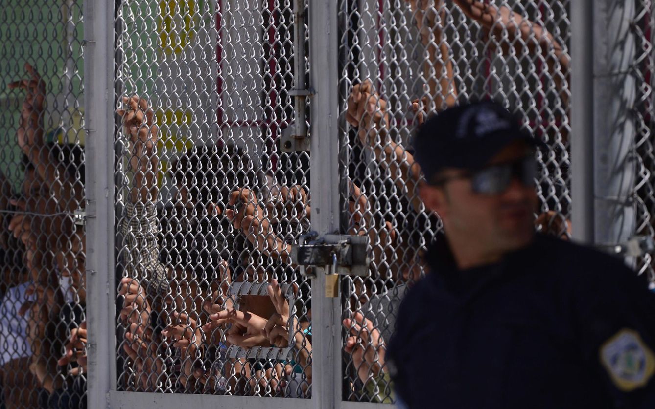 Inmigrantes y refugiados tras una valla durante la visita del Papa Francisco al campo de refugiados de Moria, en Lesbos, en abril de 2016 (Reuters)