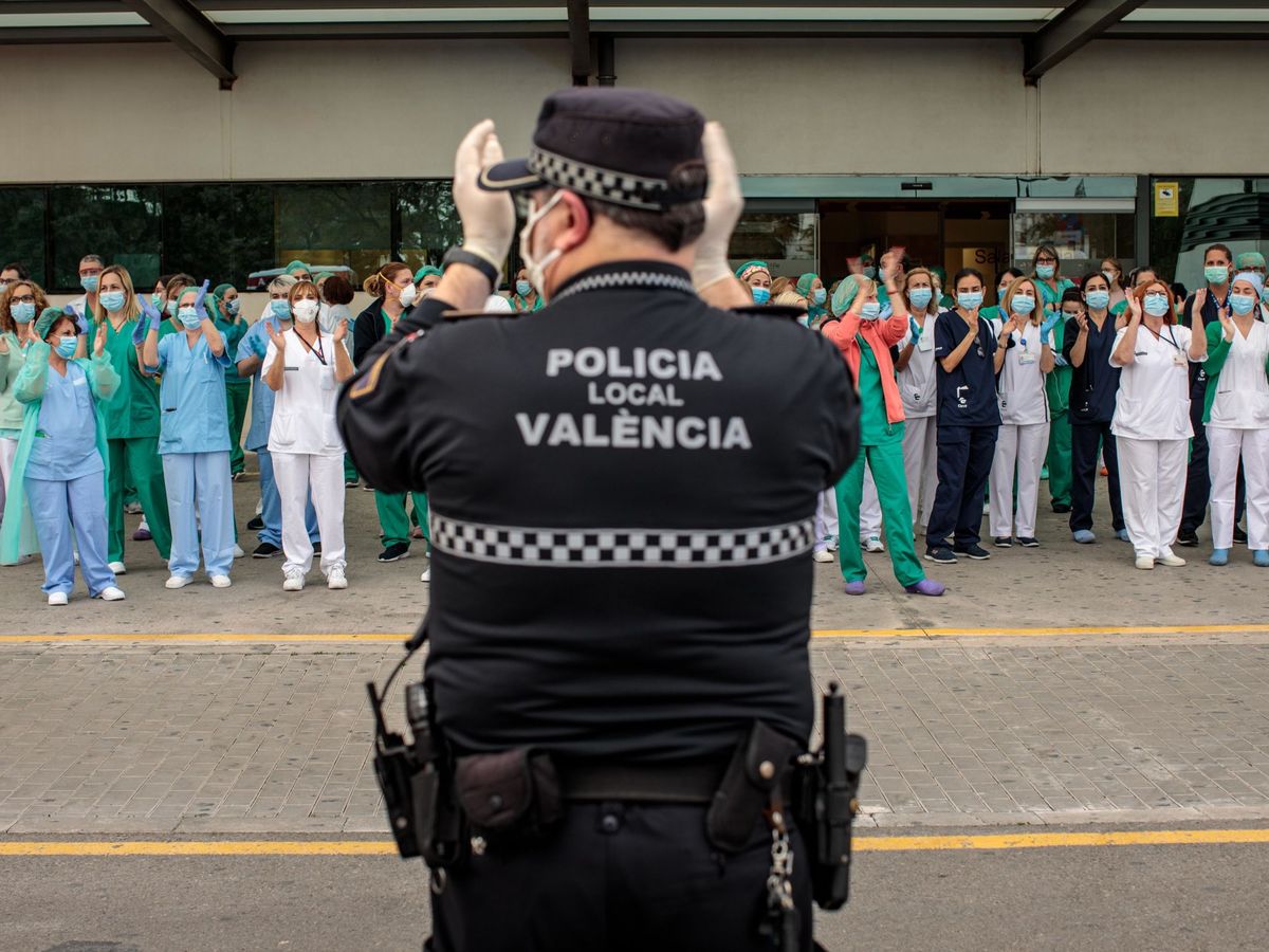 Foto: Un policía local y sanitarios del Hospital La Fe de Valencia, durante el aplauso diario. (EFE)