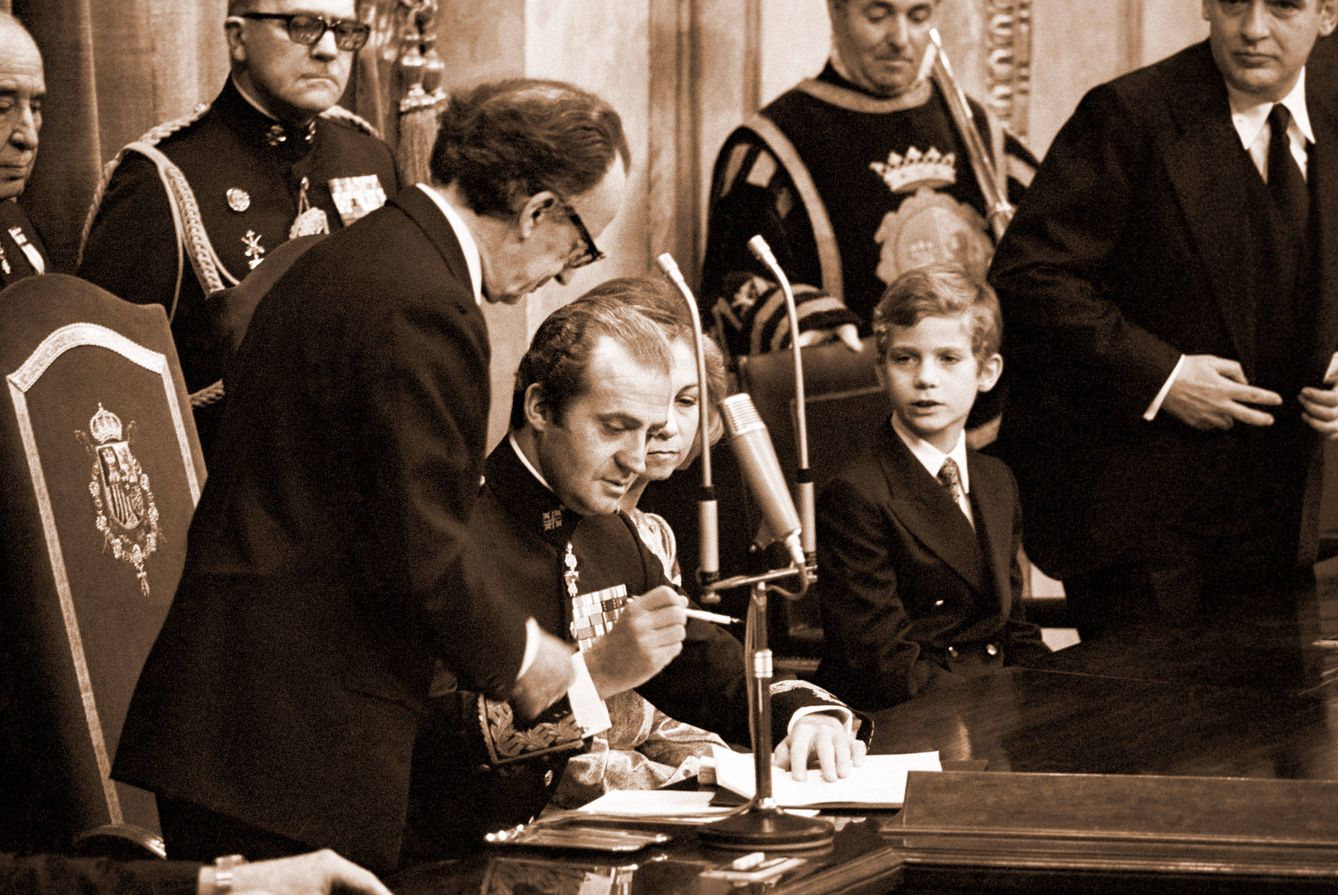 El Rey, a punto de firmar el documento, en presencia del príncipe Felipe. (EFE)