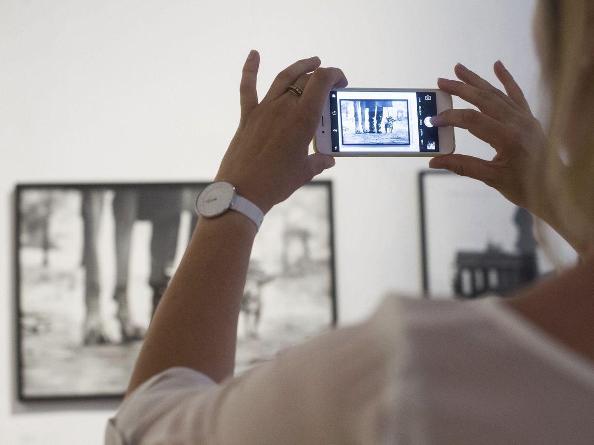 Foto: Una visitante saca una foto con el móvil a una de las instantáneas del fotógrafo Elliott Erwitt. (EFE)