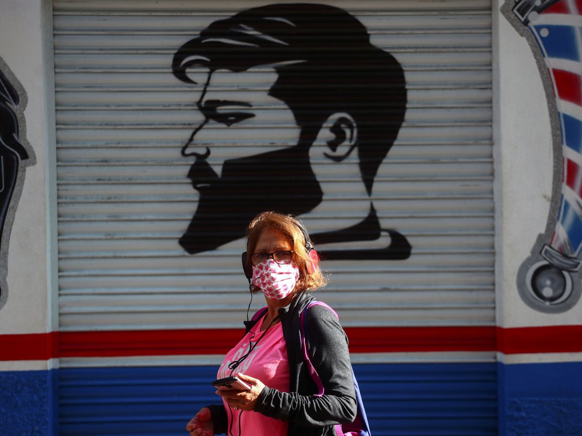 Foto: Una mujer con mascarilla pasea por Vallecas, zona afectada por las restricciones (REUTERS)