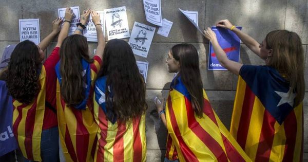 Foto: Menores de edad con esteladas cuelgan carteles a favor de votar en el referéndum del 1 de octubre. (EFE)