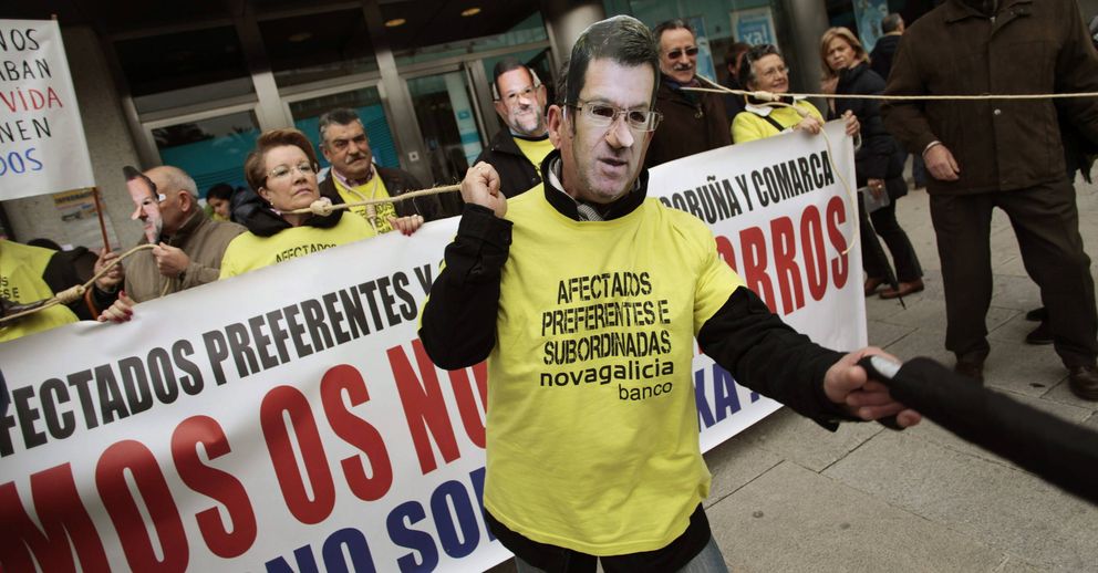 Afectados por las participaciones preferentes con máscaras de Rajoy y Núñez Feijóo. (EFE)