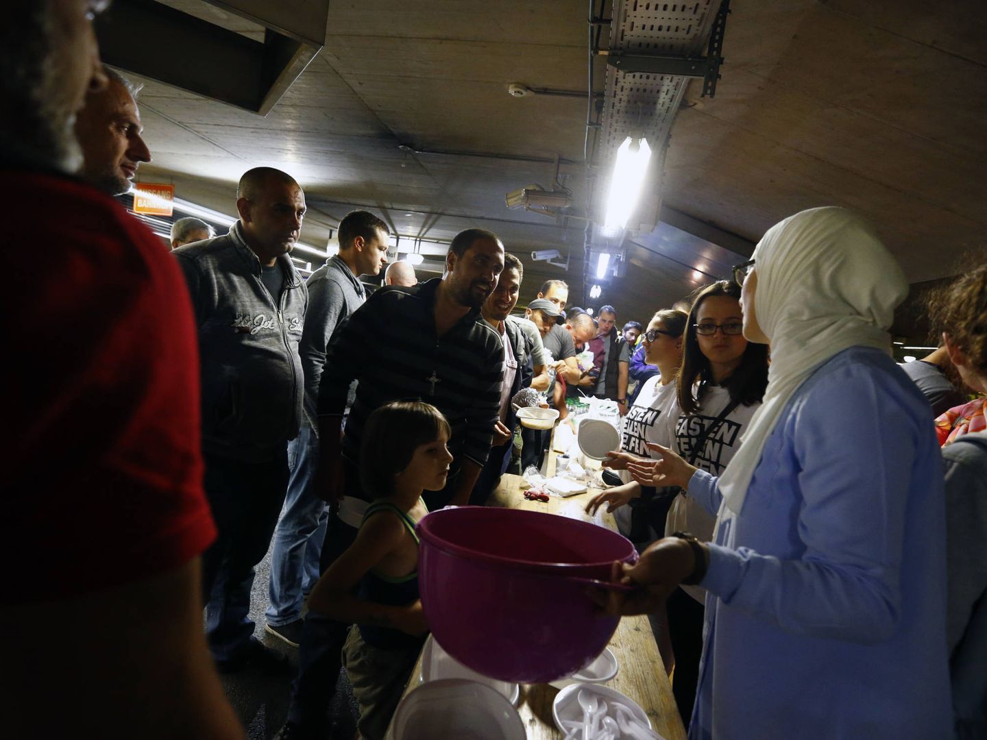 Migrantes y refugiados reciben la comida que les ofrecen unos voluntarios en Salzburgo, Austria (Reuters). 