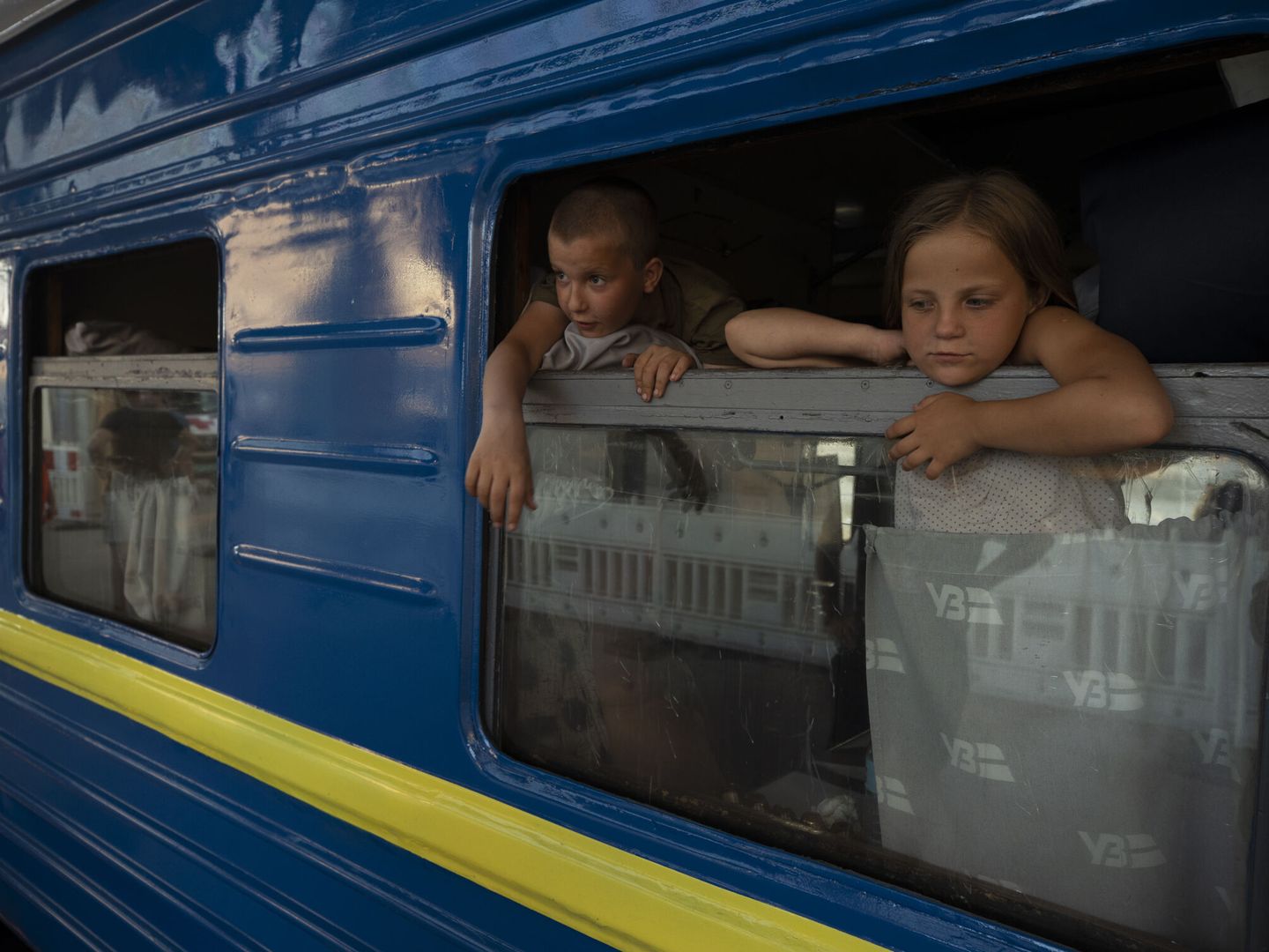Niños observan desde un vagón, donde van las personas que huyen de las zonas de combates en un tren de la 'Ukrzaliznytsia', la empresa estatal de ferrocarriles, ayer en Dnipro (Ucrania). (EFE/Orlando Barría)