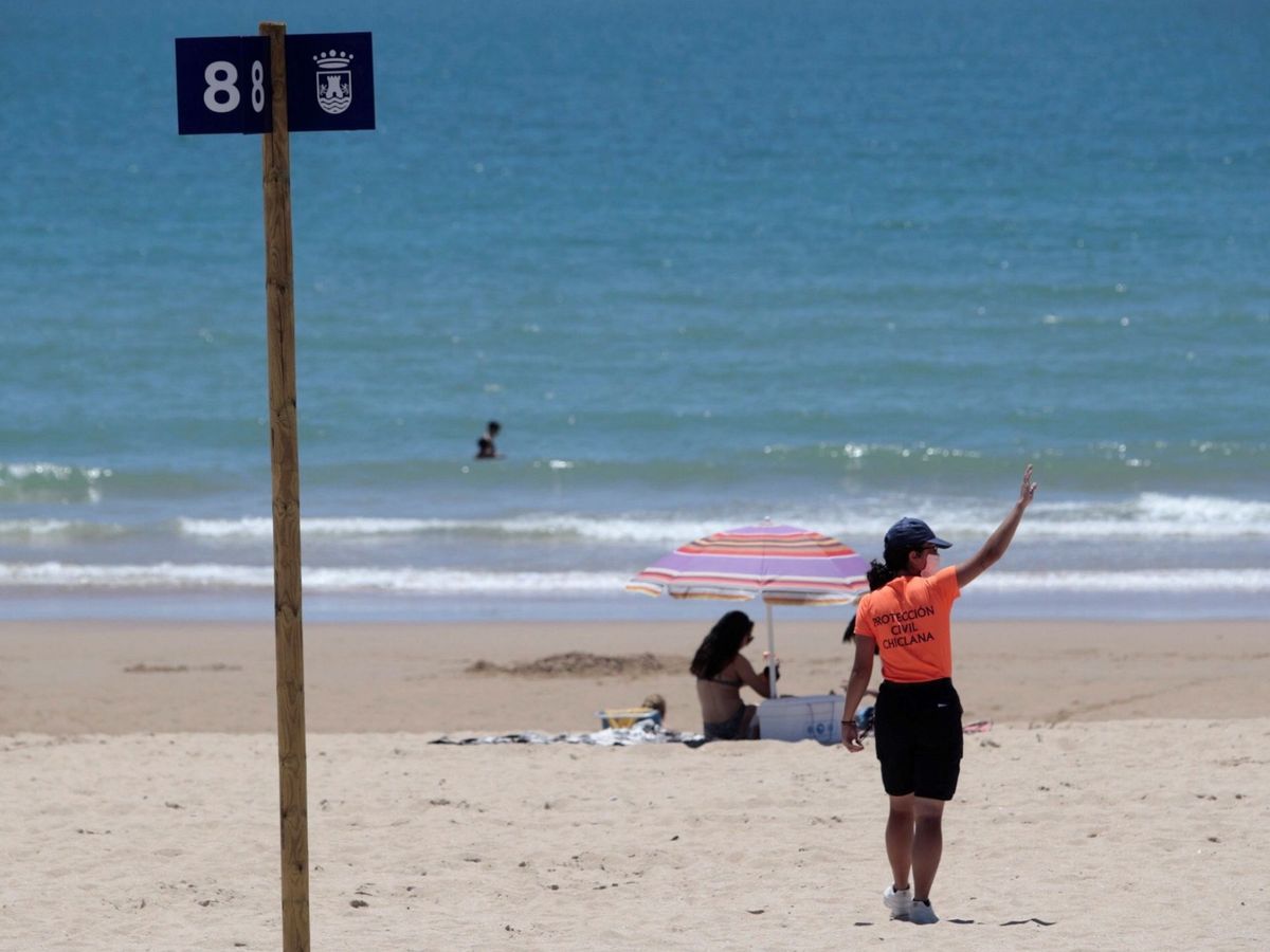 Foto: Personal de Protección Civil da indicaciones en una playa de Cádiz. (EFE)