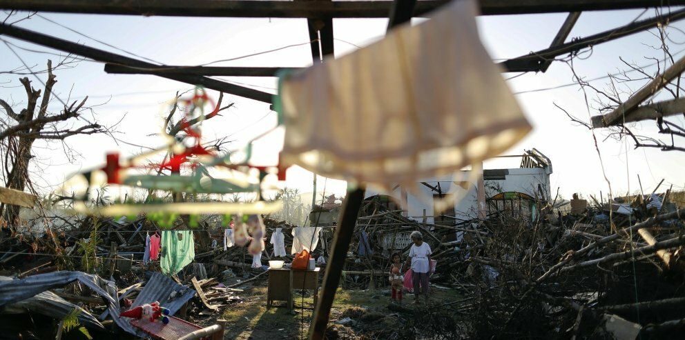 Supervivientes del tifón ante las ruinas de su casa devastada por el Haiyan (Reuters)