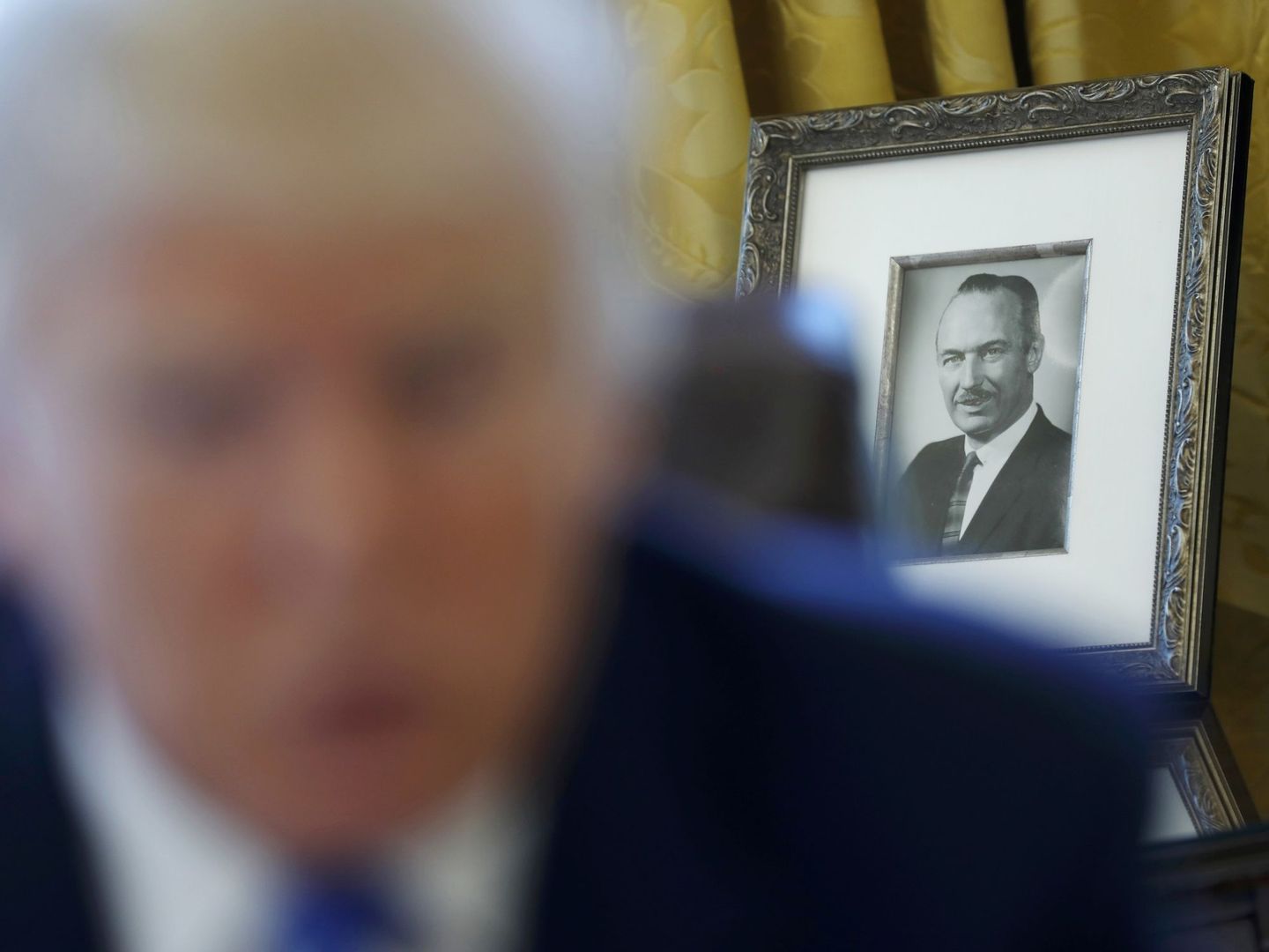 Donald Trump da una entrevista con el retrato de su padre, Fred, de fondo. (Reuters)