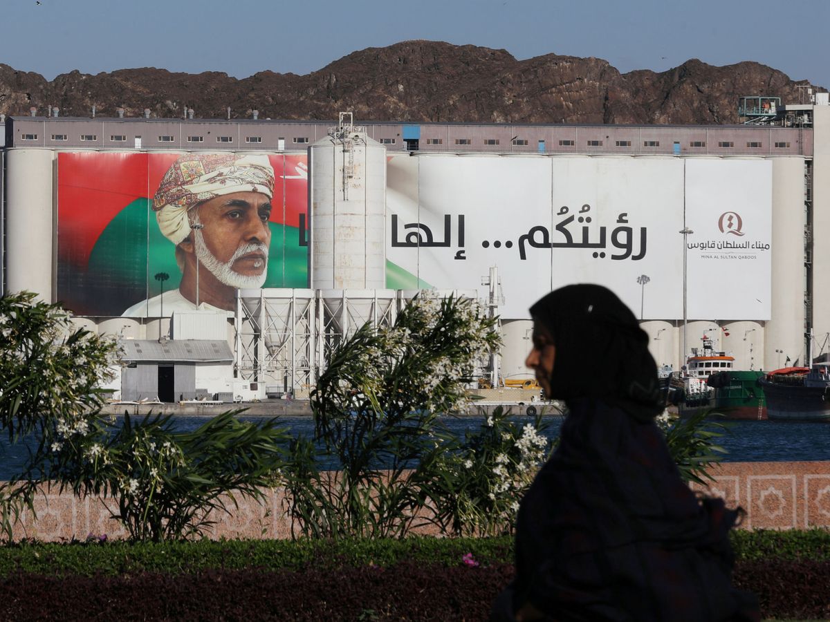 Foto: Una mujer pasa frente a un retrato del sultán Qaboos en Muscat, Oman. (Reuters)