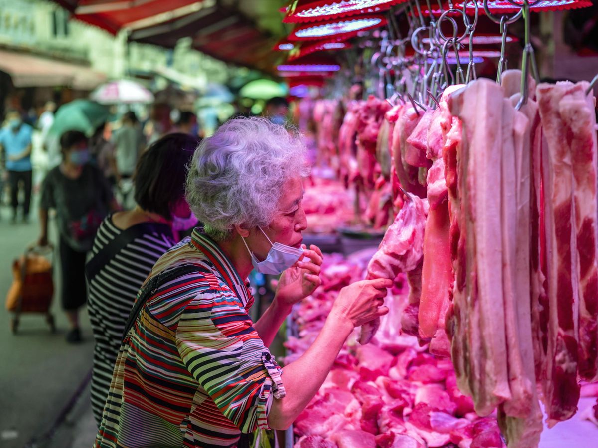 Foto: Una mujer compara varios tipos de carne en un mercado chino. (EFE)
