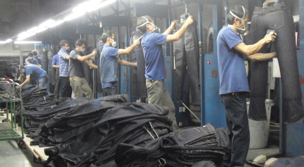Trabajadores desgastan pantalones vaqueros por el método tradicional en una fábrica de Guangdong (China) (Foto: SACOM)
