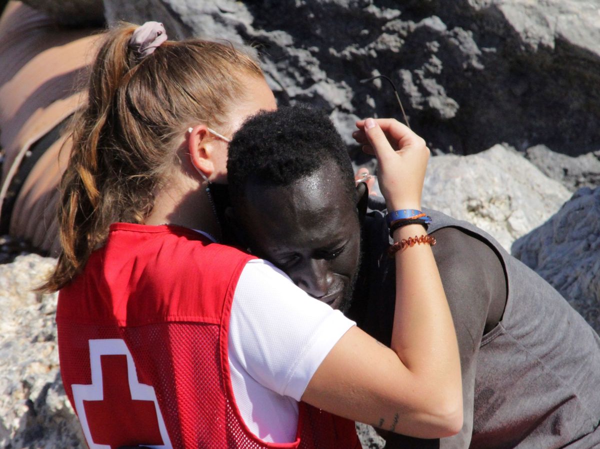 Foto: Luna consola a un migrante que ha logrado cruzar uno de los espigones fronterizos de Ceuta. (EFE)