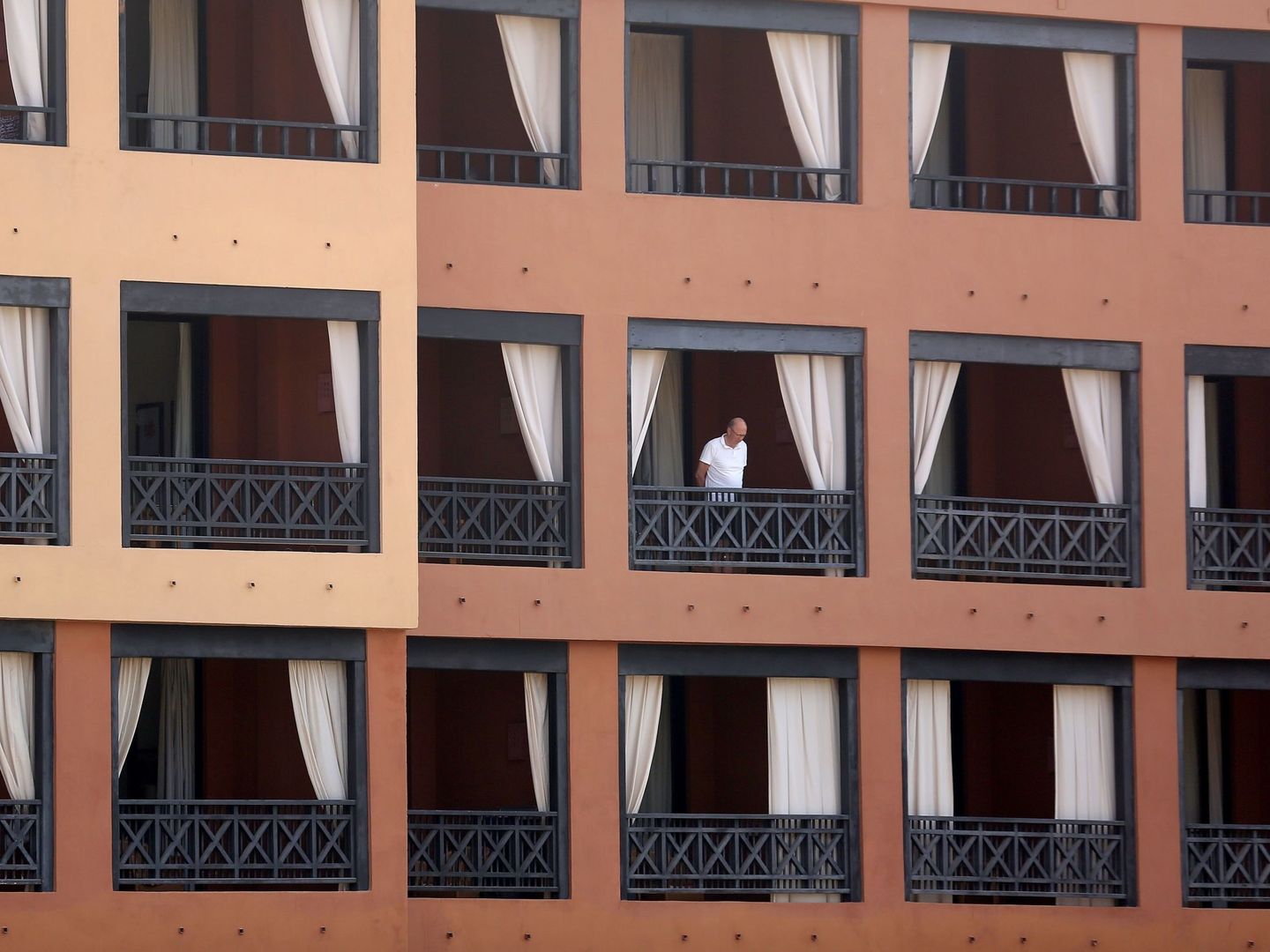 Un turista se asoma desde el balcón de su habitación en el hotel del sur de Tenerife que permanece aislado tras detectarse cuatro casos de coronavirus de Wuhan. (EFE)