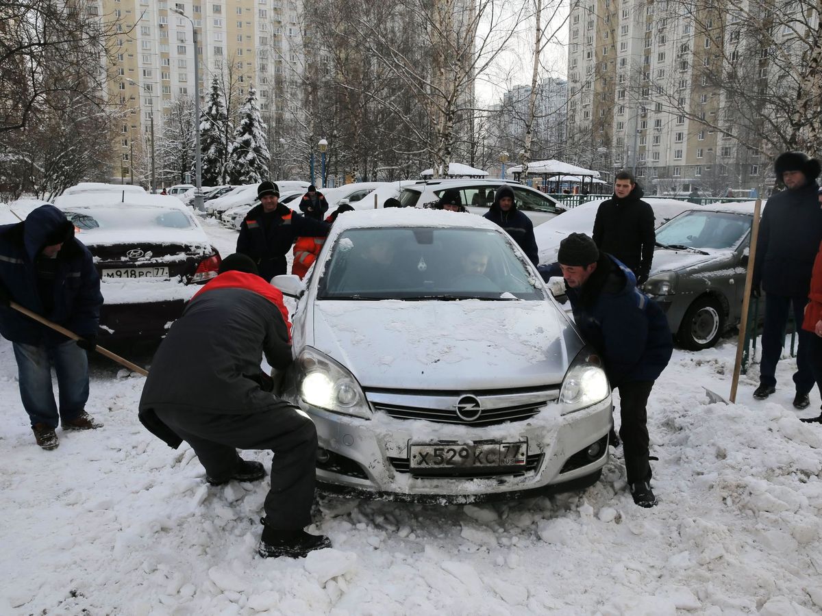 Foto: Varias personas ayudan a un trabajador municipal a empujar un coche. (EFE/Archivo/Yuri Kochetkov)