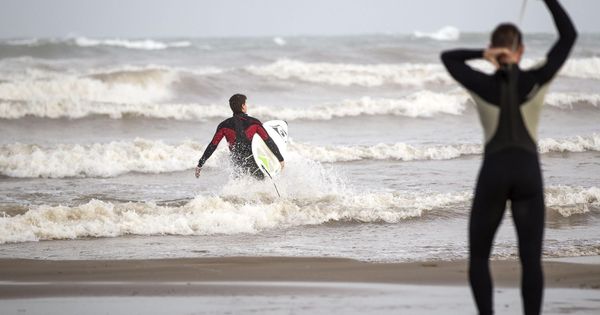 Foto: Dos jóvenes surfistas en la playa de Las Arenas de Valencia (EFE/Manuel Bruque)