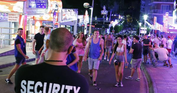 Foto: A security worker looks at tourists walking at Punta Ballena street in Magaluf, on the Spanish Balearic island of Mallorca,