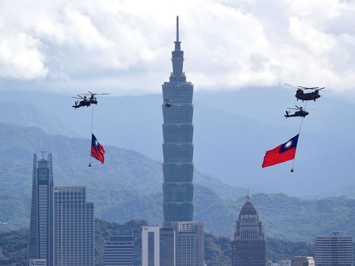 Foto: Varios helicópteros izan banderas gigantes de Taiwán mientras vuelan cerca de la torre Taipei 101. (EFE)