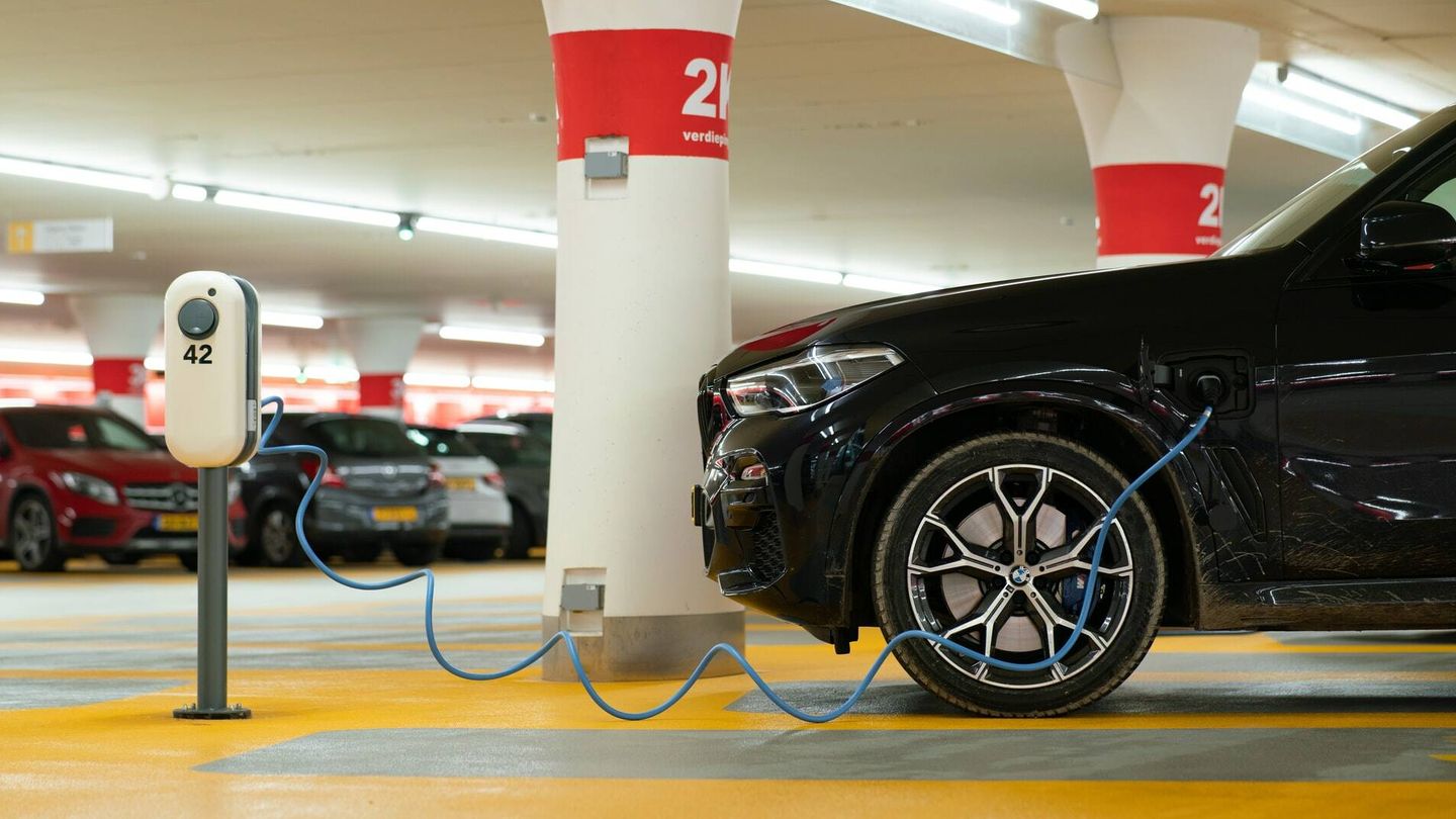 Un coche eléctrico recarga su batería en un estacionamiento. 