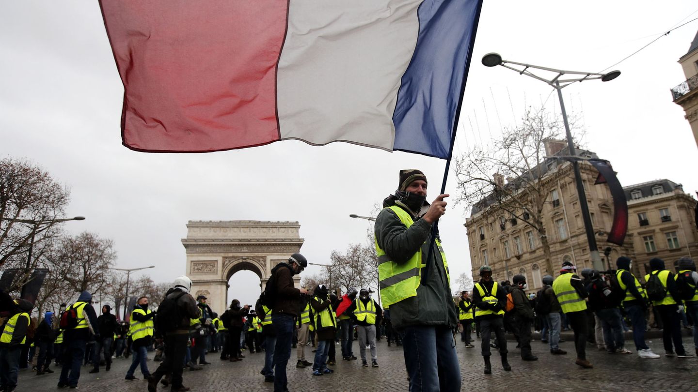 Un manifestante con una bandera francesa durante una protesta de los chalecos amarillos en París. (EFE)