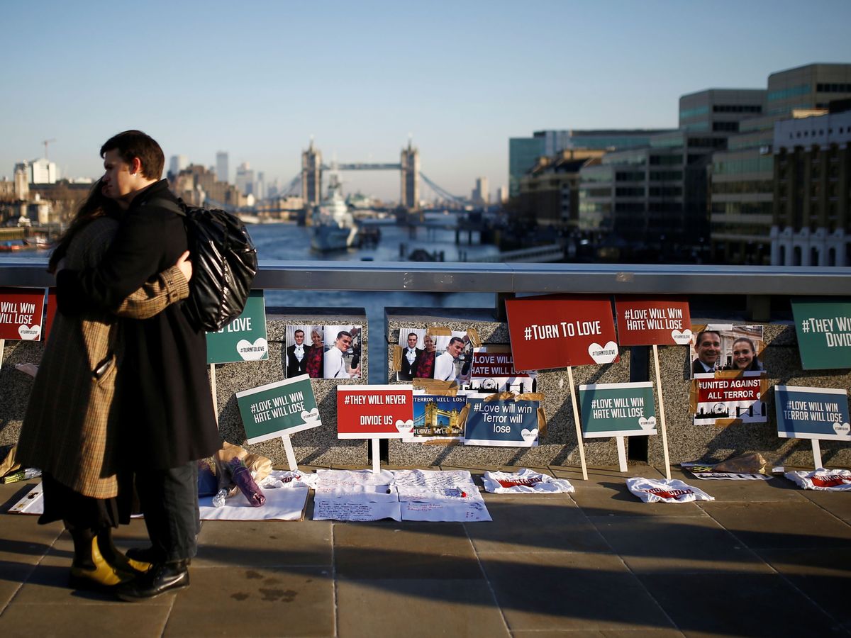 Foto: People embrace each other in front of placards and tributes to victims on london bridge in london