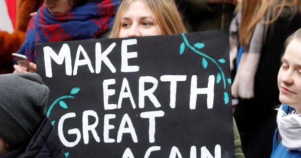Foto: Una estudiante sostiene una pancarta en la que puede leerse "Haced la Tierra grande de nuevo". (EFE)