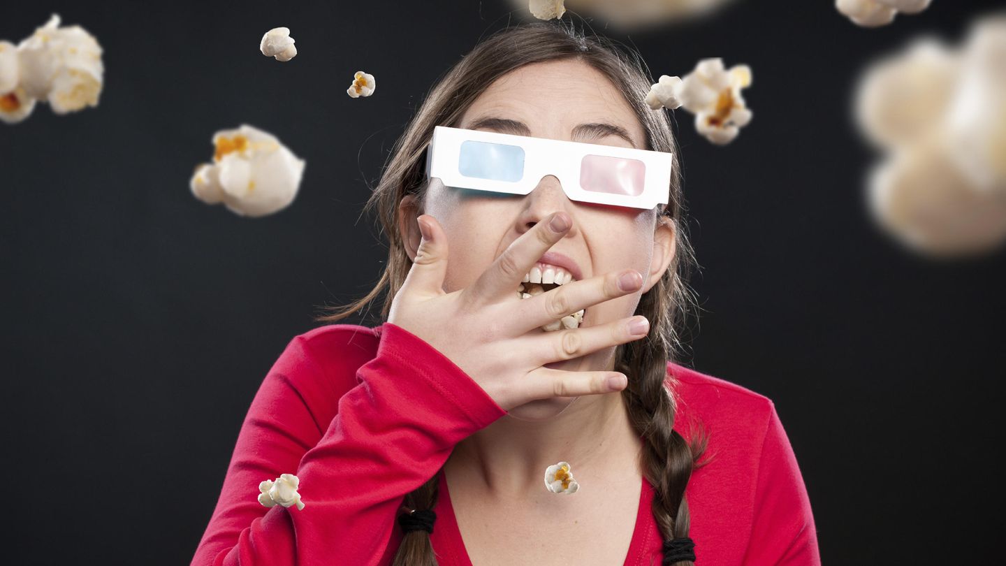 Una joven come palomitas durante una sesión de cine en 3D