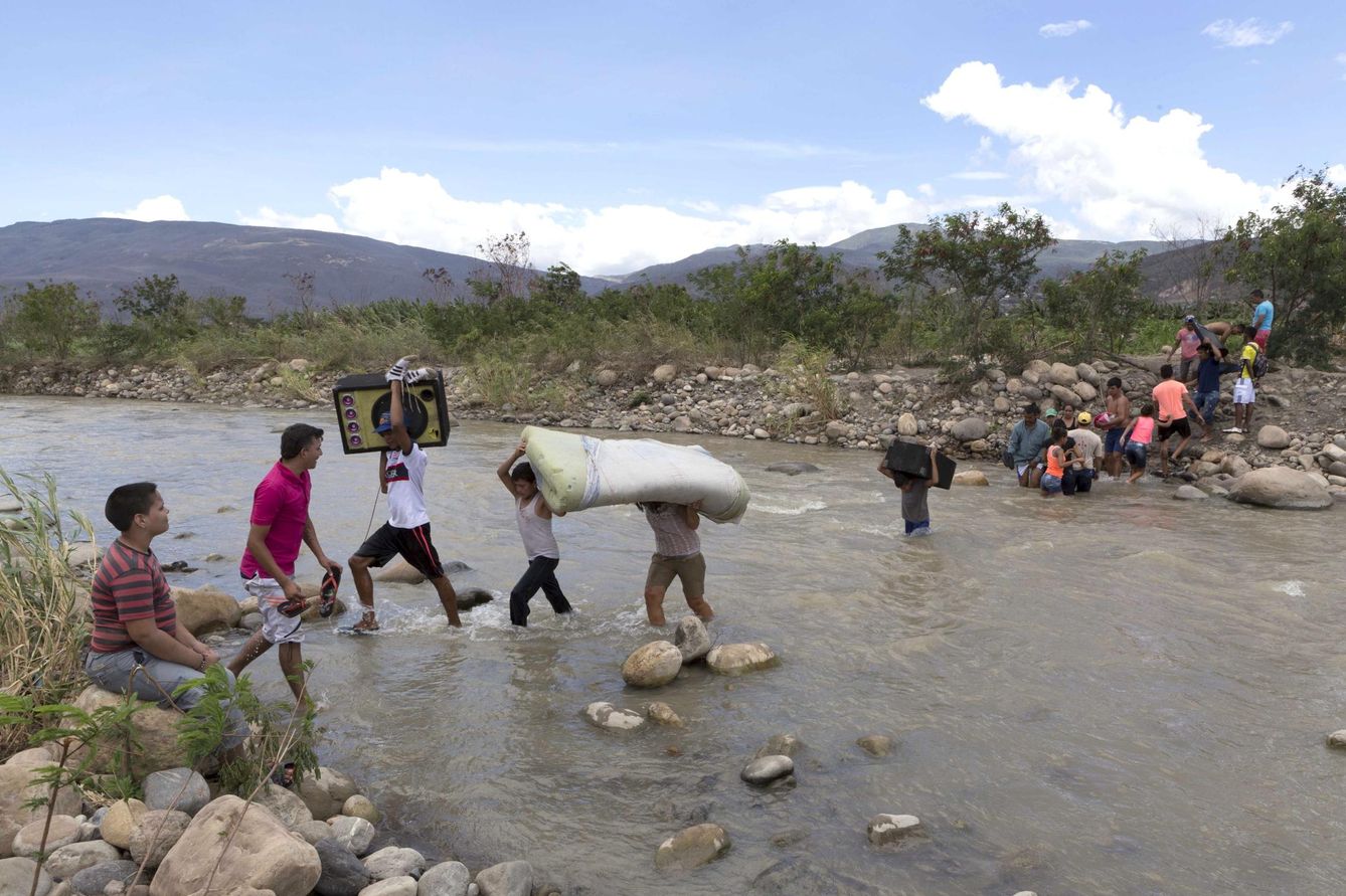Un grupo de colombianos transporta objetos sobre el río Táchira, en agosto de 2015. (Reuters)