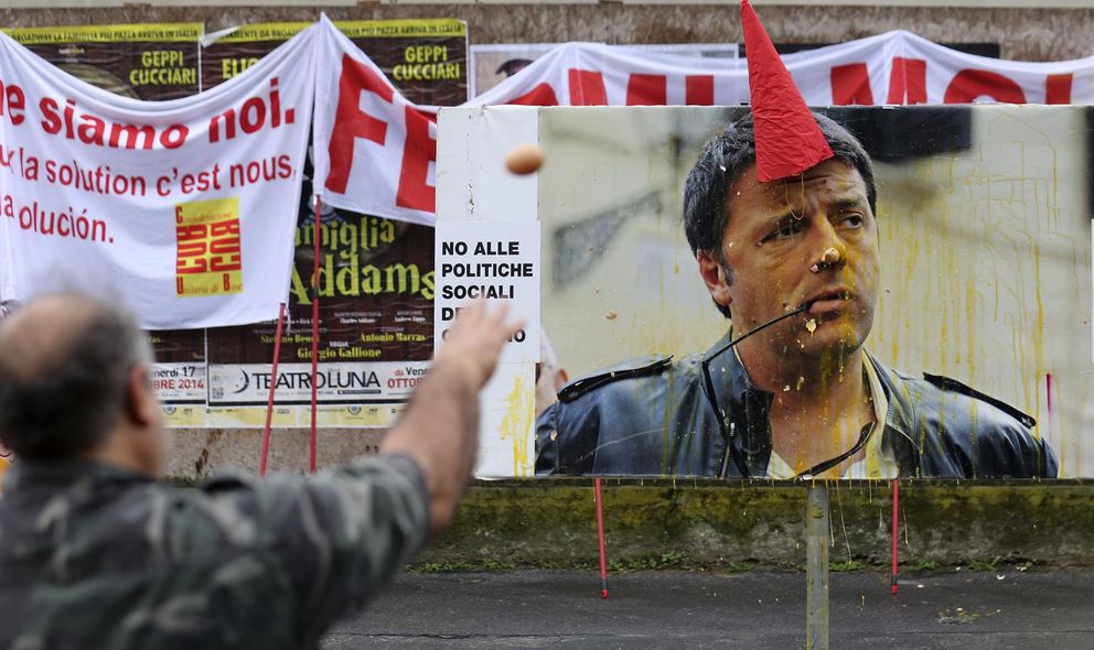 Un manifestante arroja huevos contra un cartel de Matteo Renzi durante una cumbre sobre empleo en Milán (Reuters).