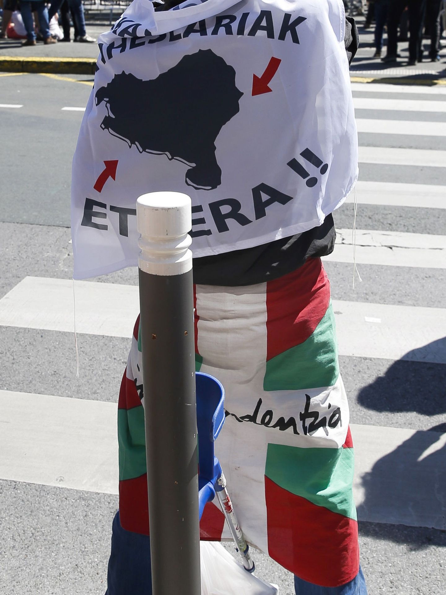 Una persona se cubre con una bandera a favor del acercamiento de los presos de ETA y con una ikurriña. (EFE)