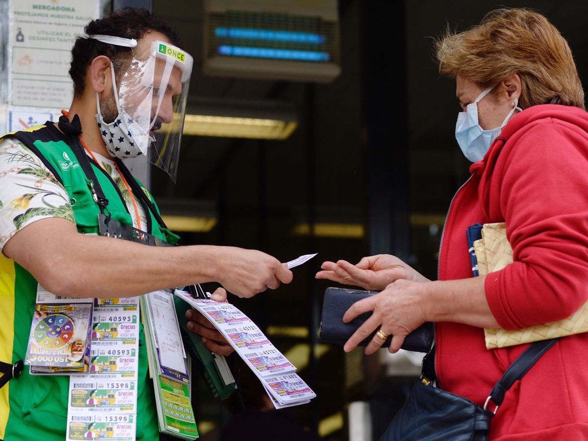 Foto: Un vendedor de la ONCE entrega su cupón a una mujer (EFE)