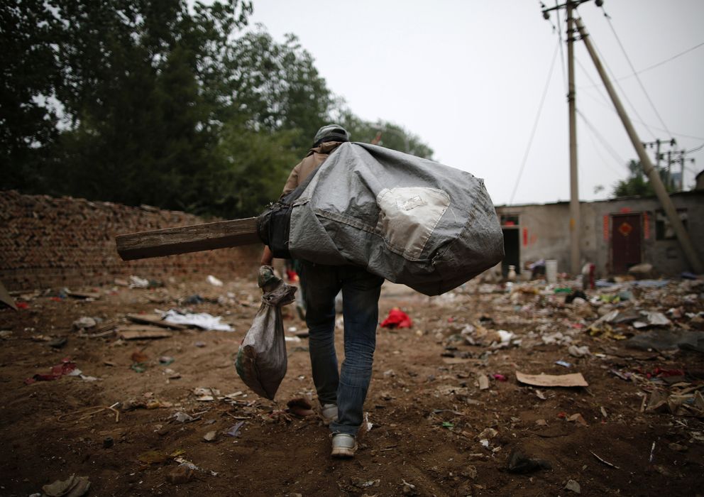 Foto: Un recolector de basura carga con un saco lleno de restos de equipos electrónicos (Reuters). 