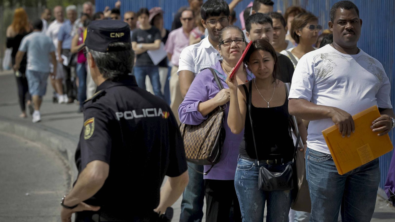 Foto: Inmigrantes hacen cola a la entrada de la Brigada Provincial de Extranjería y Fronteras del CIE de Aluche en Madrid. (EFE)