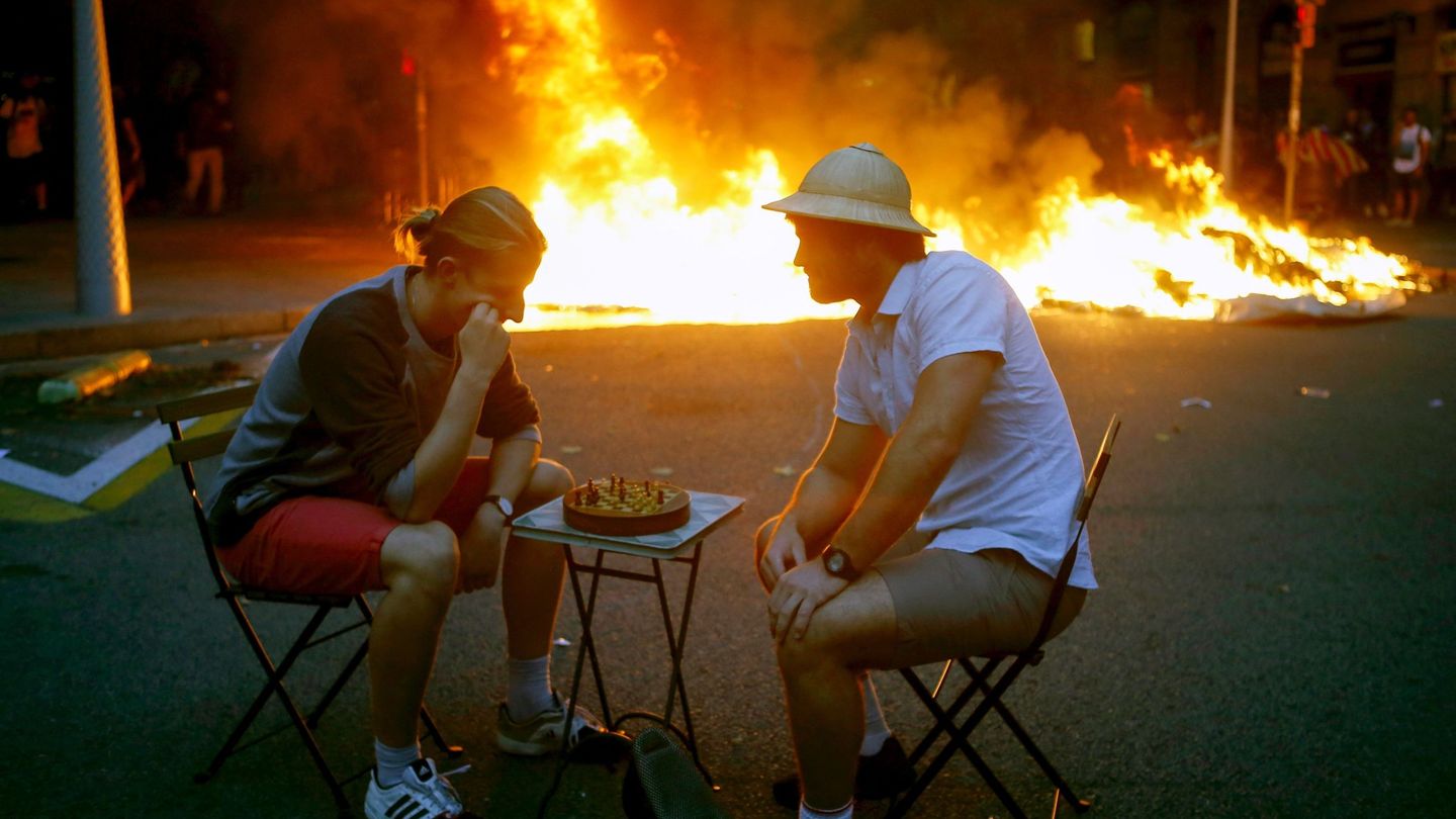 Dos hombres bromean jugando al ajedrez en medio de los disturbios en Barcelona. (EFE)
