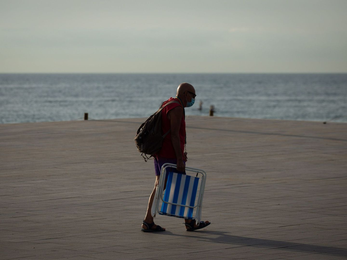 Un ciudadano se dirige hacia la playa de la Barceloneta en Barcelona, inusualmente vacía de turistas. (EFE)