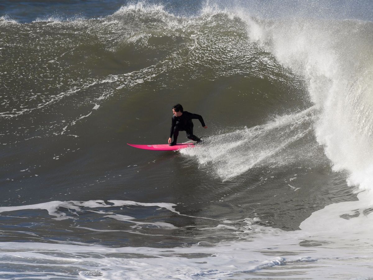Foto: Un hombre practica surf en la playa de San Lorenzo de Gijón. (EFE/Eloy Alonso)