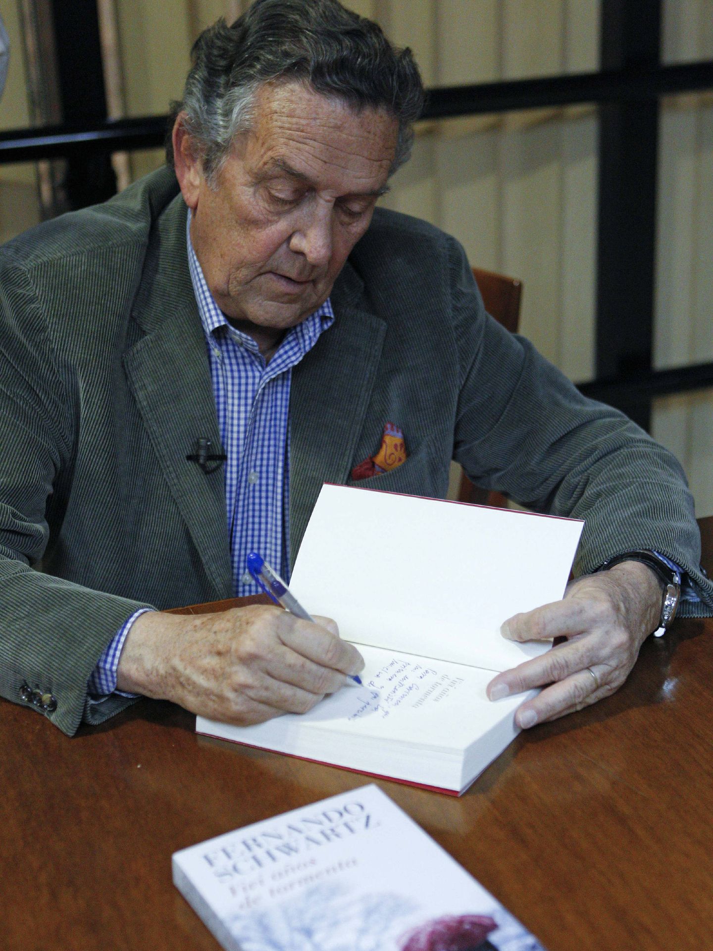 El escritor Fernando Schwartz firma un ejemplar de su novela, 'Viví años de tormenta'. (EFE/Mondelo)