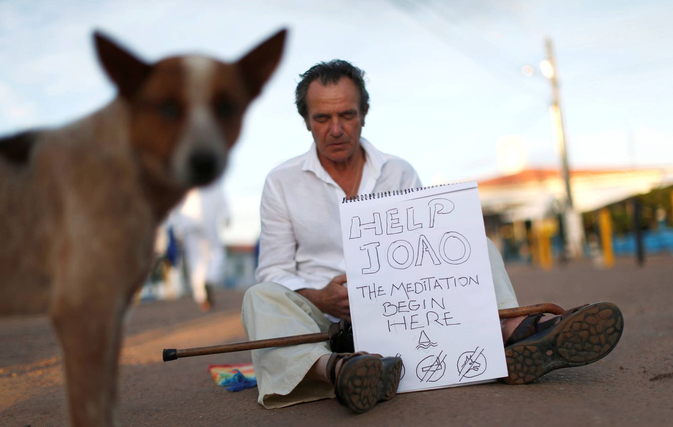 Un seguidor del médium Joao de Deus  sostiene un cartel en el 'centro curativo' de Abadiania, Brasil. (Reuters)