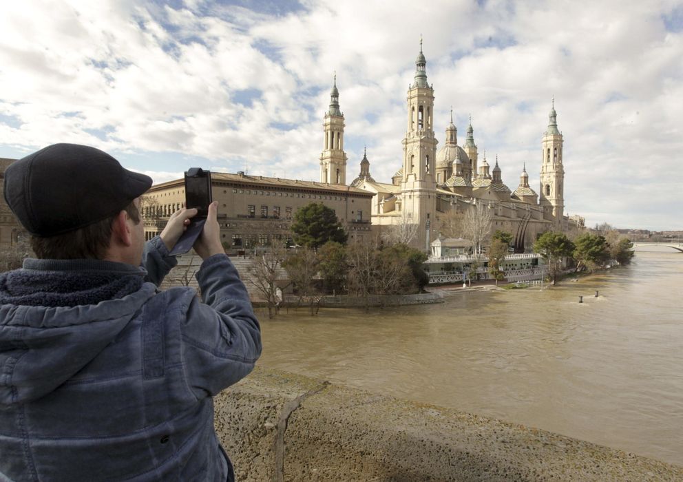 Foto: Un hombre fotografía la Basílica del Pilar de Zaragoza con el río Ebro a sus pies. (Efe)