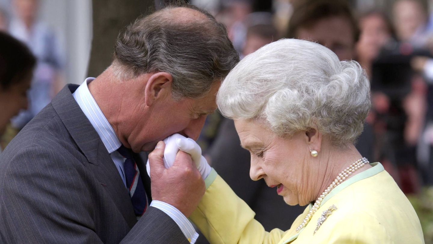 La reina Isabel II con sus inseparables guantes dándole la mano a su hijo, el actual rey Carlos III. (Getty)