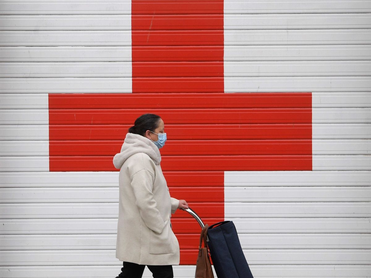 Foto: Una mujer camina con mascarilla ante el Hospital de La Cruz Roja. (EFE)