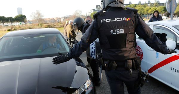 Foto: Efectivos de la Policía Nacional entre un vehículo de licencia VTC y un taxi a las puertas del recinto ferial de IFEMA. (EFE)